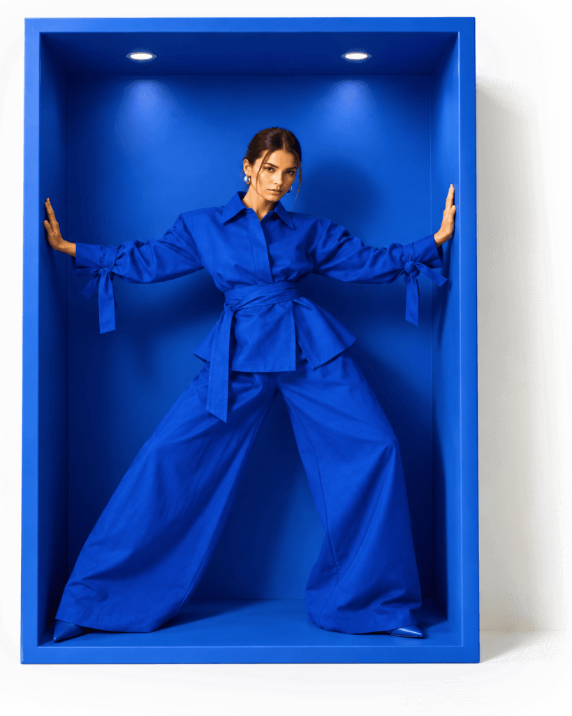 Modelo de camisa e calça azul posando dentro de um nicho azul