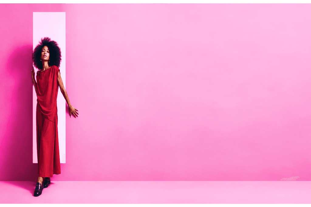 Modelo com vestido vermelho em fundo rosa